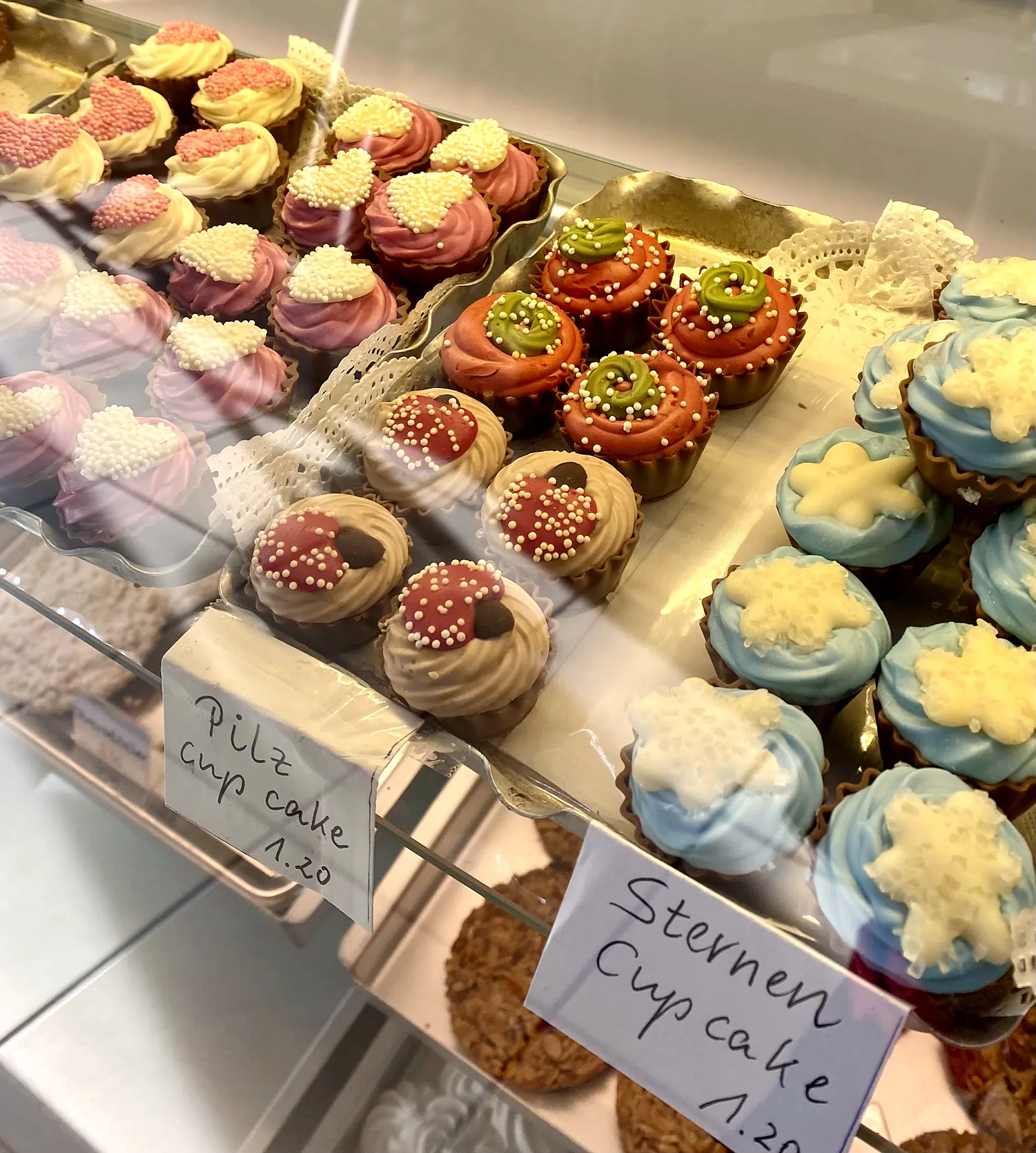 Cupcakes mit bunter Verzierung in der Vitrine