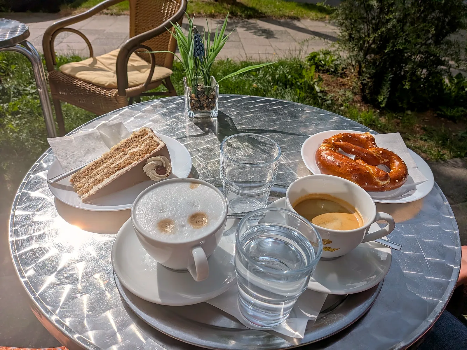 Runder Tisch draußen mit Torte, Cappuccino, Espresso und Breze