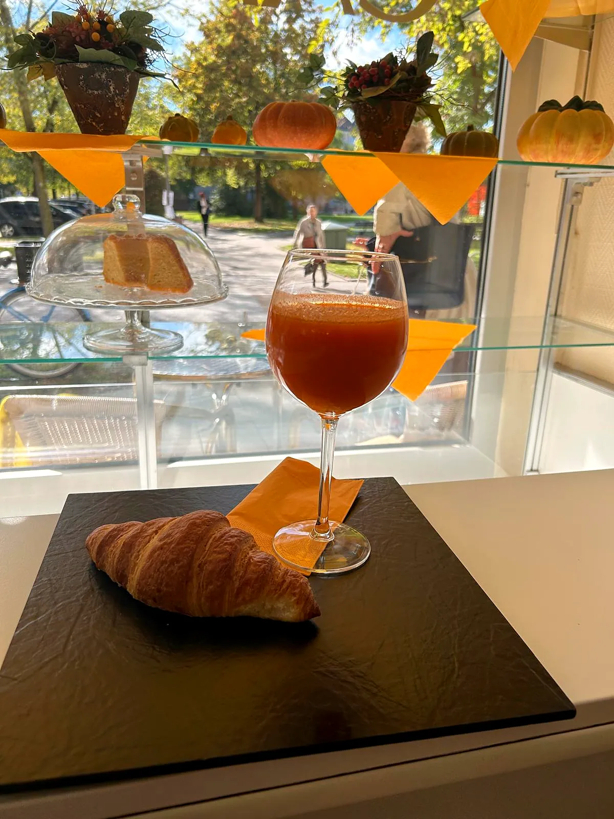 Ein Glas frisch gepresster Saft und ein Croissant am Fenster des Cafés