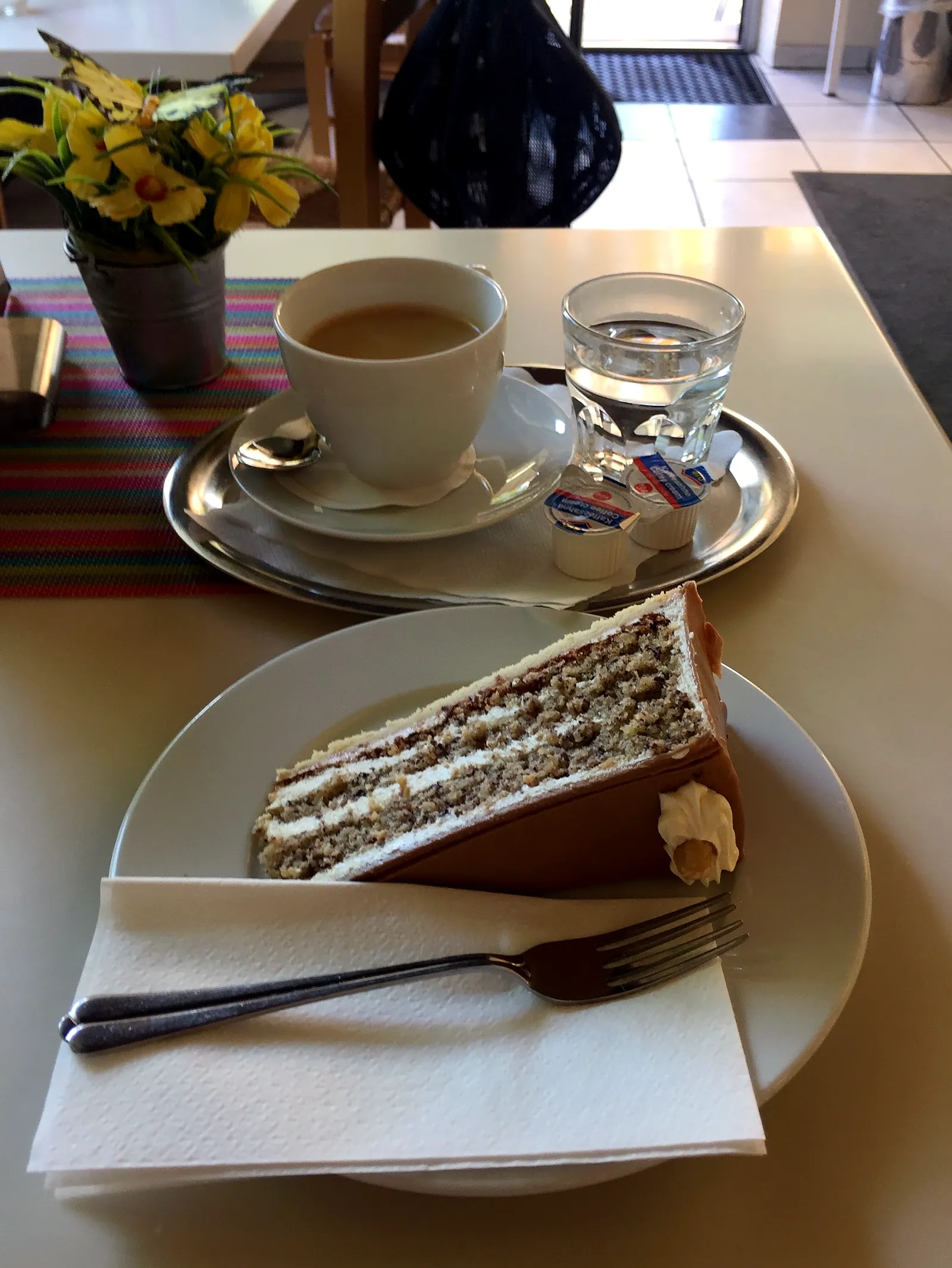Ein Stück Torte mit Kaffee am Fenstertisch